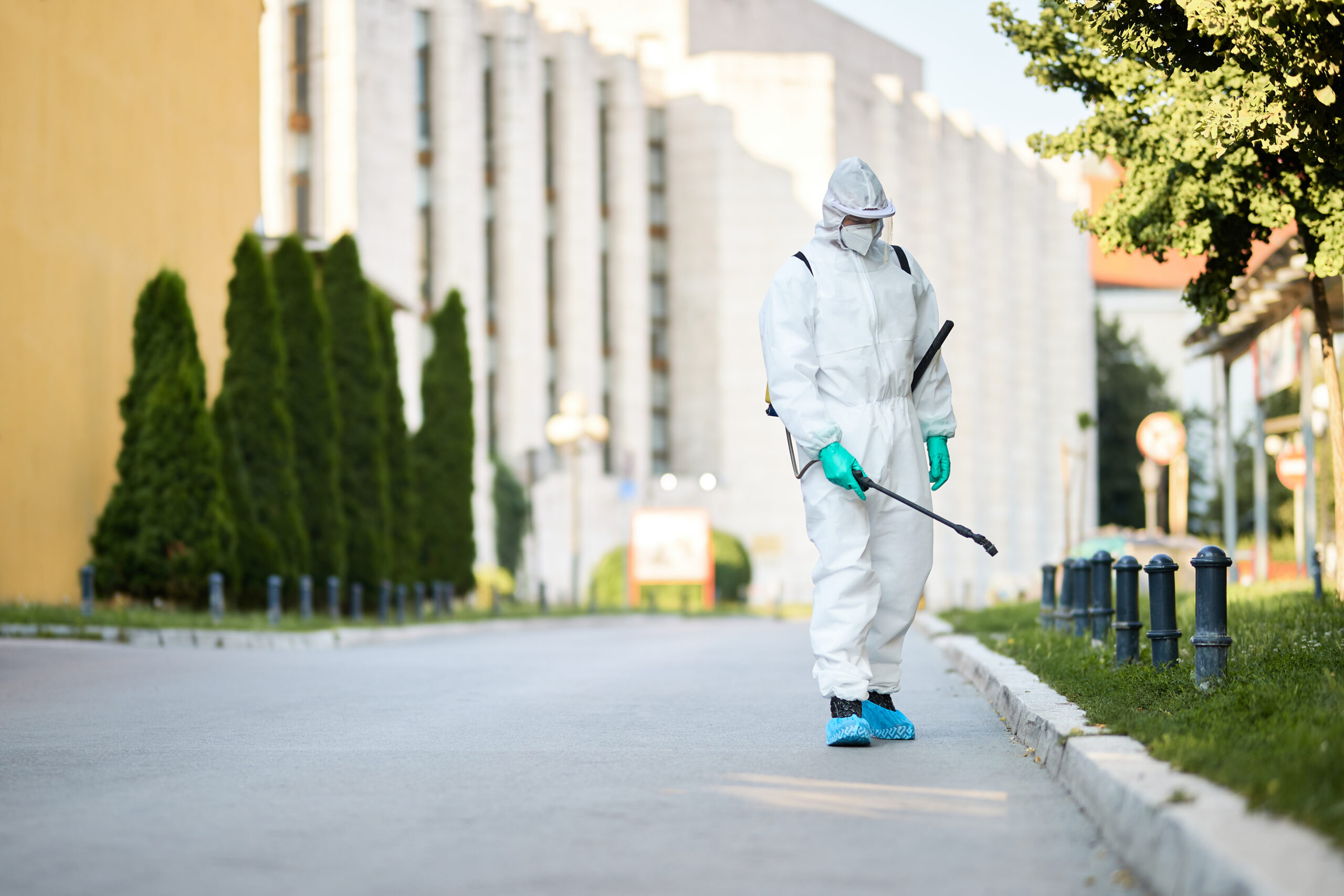Man in protective suit disinfecting city streets during coronavi